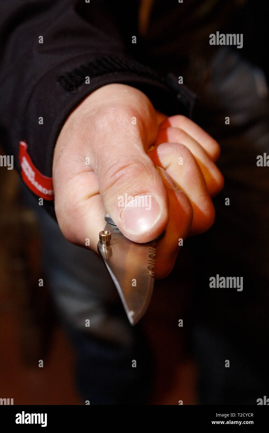 Knife crime. Hooded man brandishing a butterfly knife Stock Photo