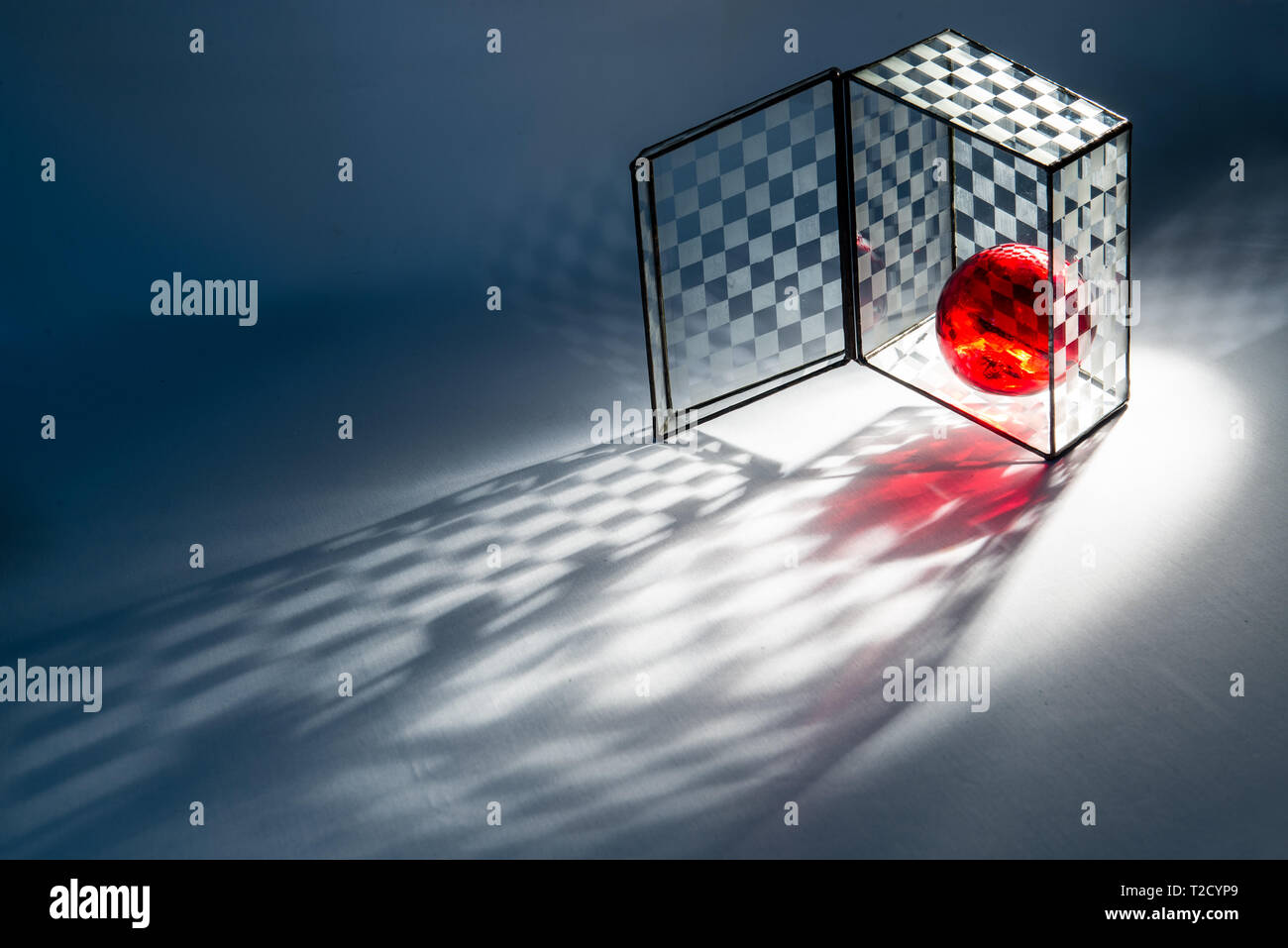 Red glass ball in checkered glass box. Stock Photo