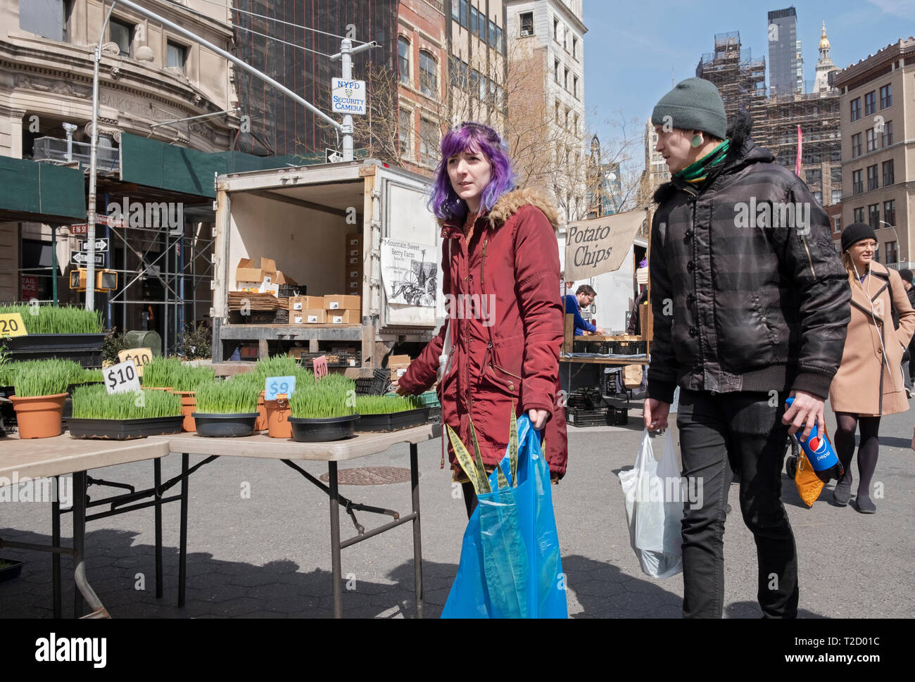 A young man & a lady chack out wheat grass at the Union Square Market in Manhattan, New York City. Stock Photo