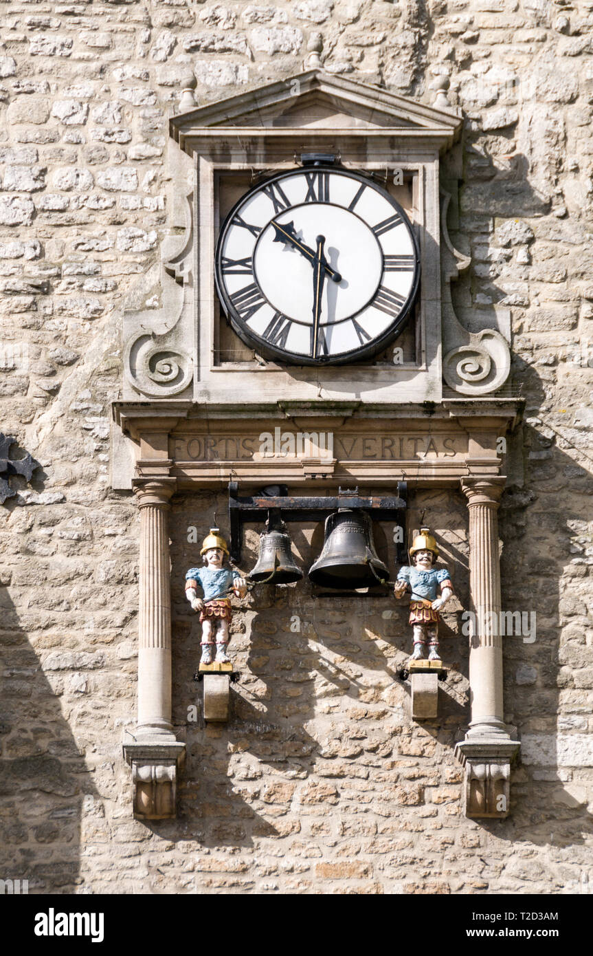 A large mounted wall clock on the Carfax Tower with a pair of bells and mechanical figures called 'quarterboys' which hammer out the quarter hour on b Stock Photo