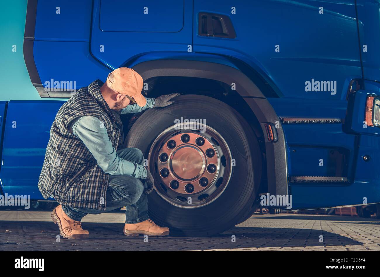 Caucasian Driver Checking Semi Truck Wheels Looking For Potential Issues. Transportation Industry Safety. Stock Photo