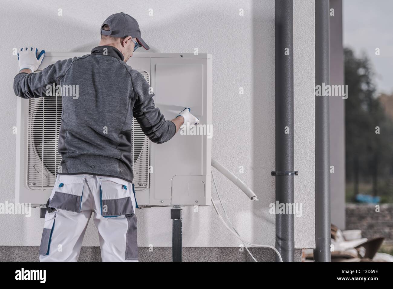 Heat Pump Replacing by Professional Caucasian Heating Technician. Industrial Theme. Stock Photo