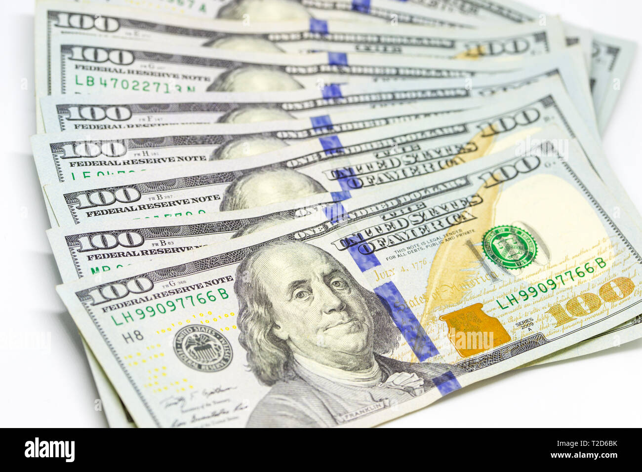 A group of one hundred dollar bills arranged and displayed on white