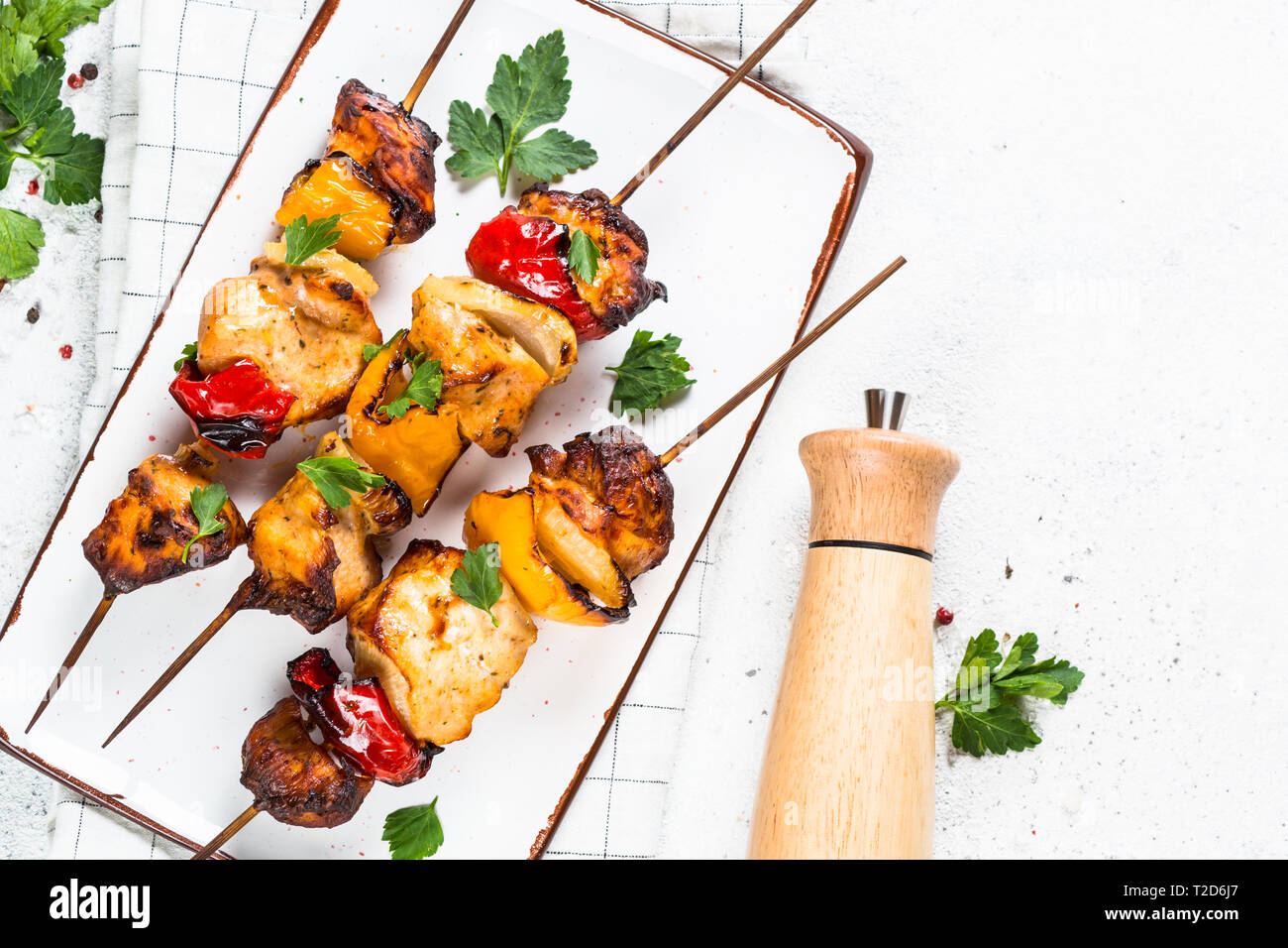Chicken kebab or shashlik with vegetables on skewers on white stone table. Top view with copy space. Stock Photo
