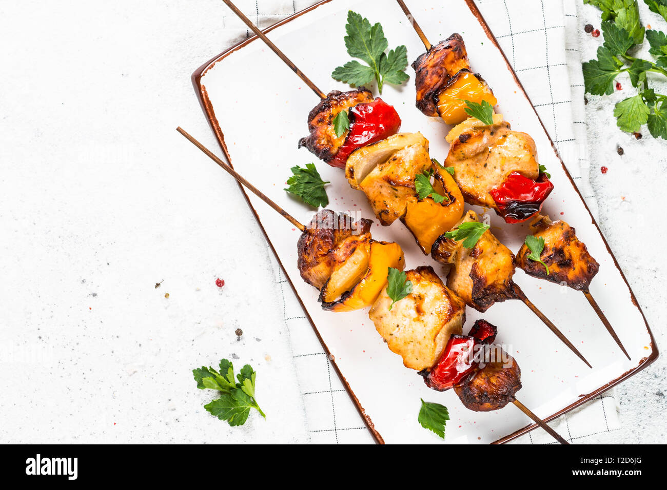 Chicken kebab or shashlik with vegetables on skewers on white stone table. Top view with copy space. Stock Photo