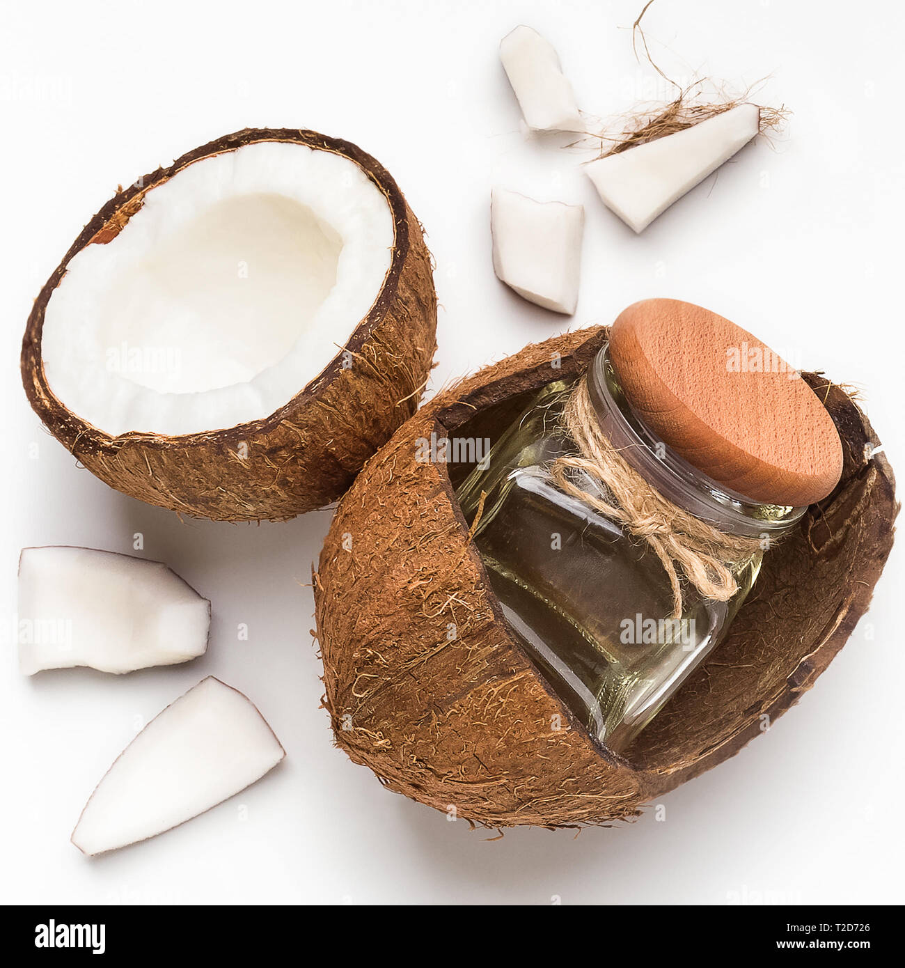 Copped coconut and jar of coconut oil in coco shell on white background ...