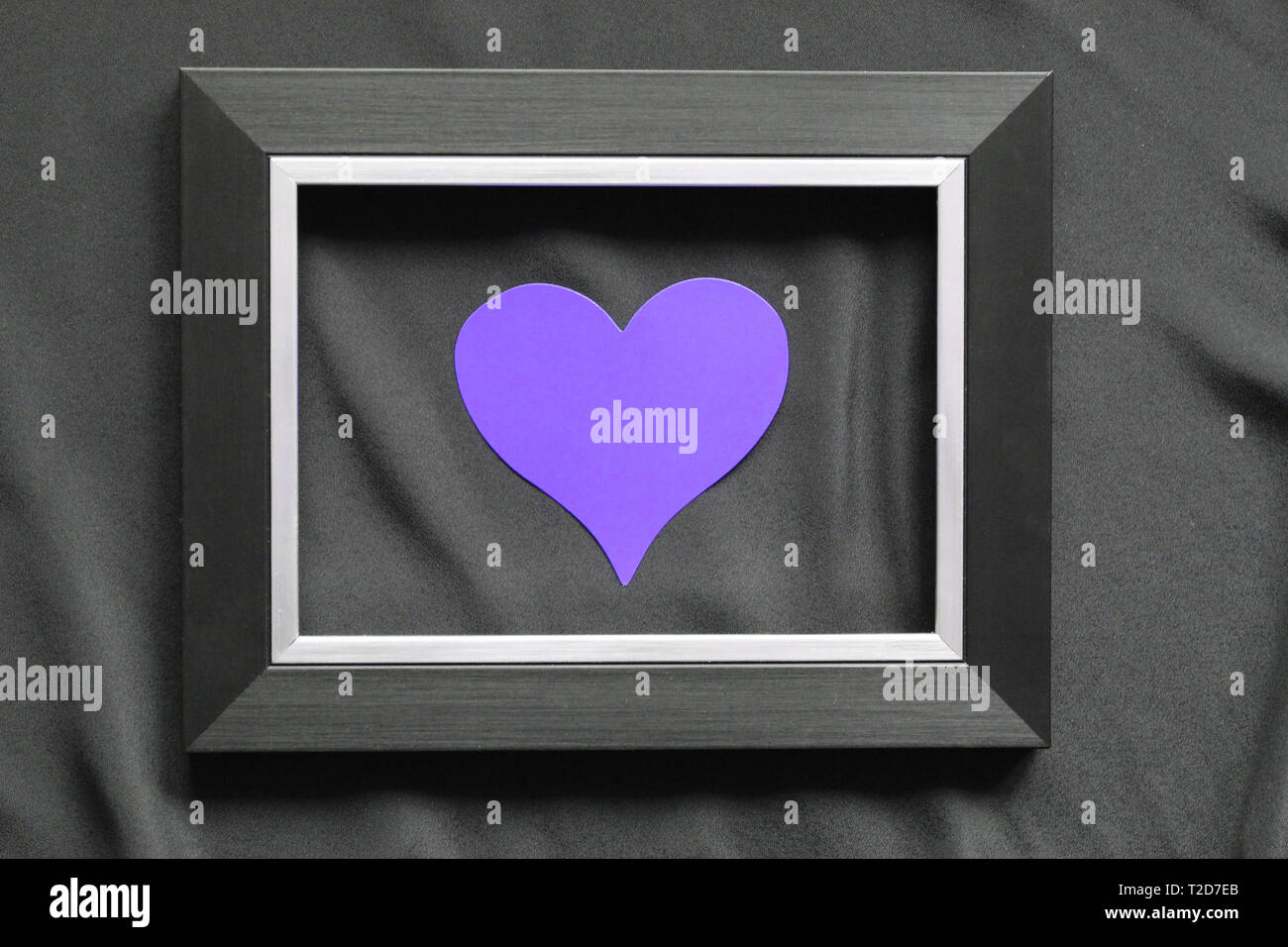 Black frame on a black background, near the heart. Flatly. Place for text. Template for postcards. Stock Photo