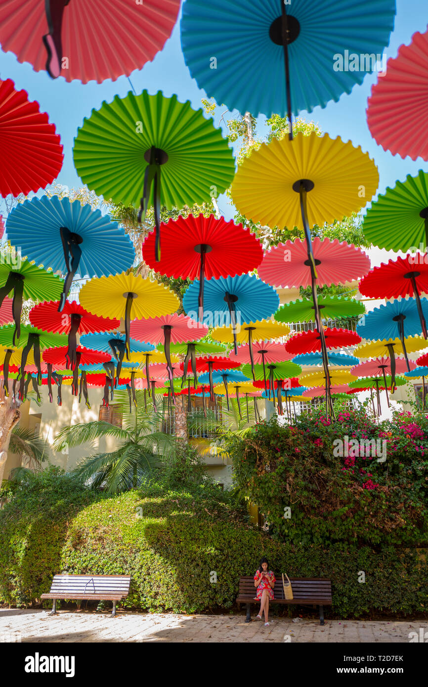 Colourful parasols strung up together over a park on a blue sky background Stock Photo