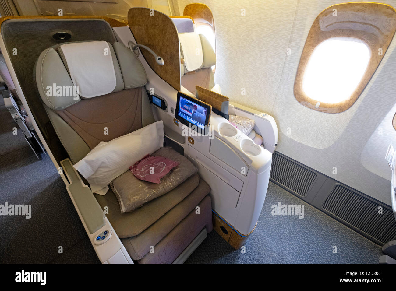 Spacious business class empty window seats with pillows and multimedia screen on a Emirates commercial flight airplane Stock Photo
