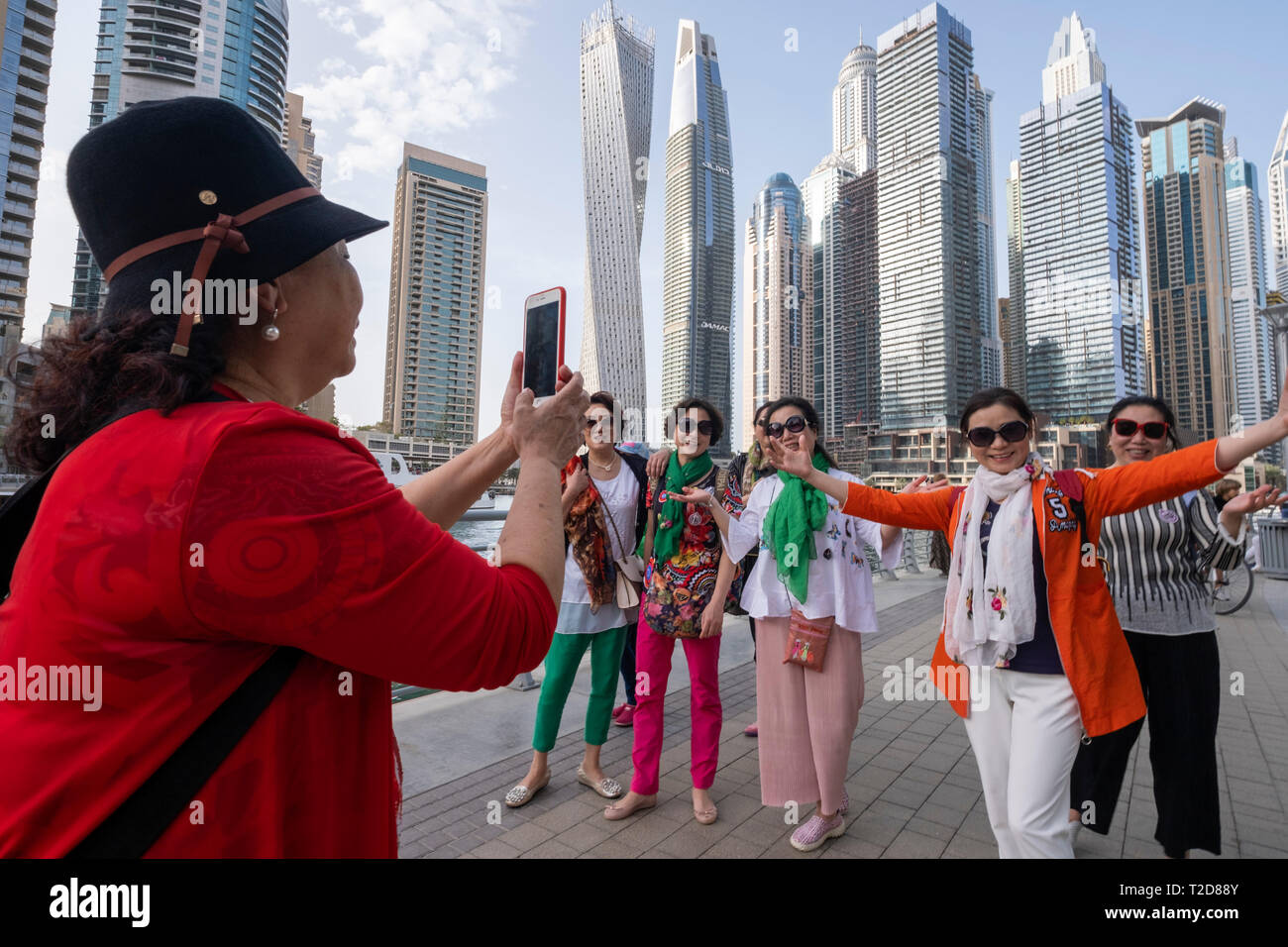 Asian tourists posing for photographs at the Dubai Marina, Dubai, United Arab Emirates Stock Photo