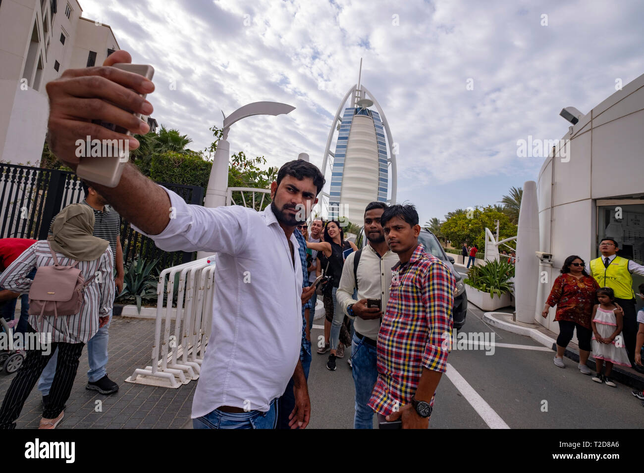 Group of tourists taking a selfie in front of the Burj Al Arab Jumeirah Hotel in Dubai, United Arab Emirates Stock Photo