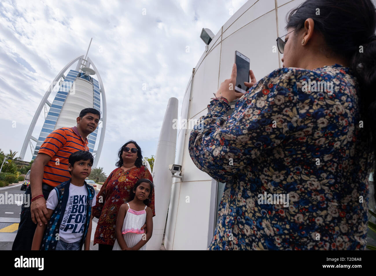Family pose for photographs in front of the Burj Al Arab Jumeirah Hotel in Dubai, United Arab Emirates Stock Photo