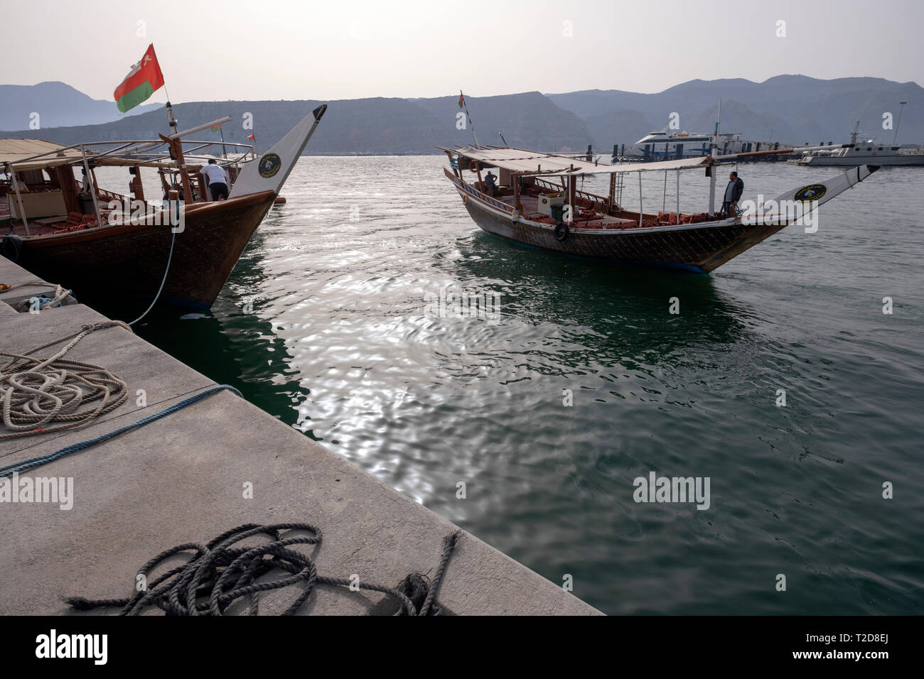 Cruise tour aboard a traditionally decorated arabian Dhow wooden boat along the rocky mountains of the Musandam peninsula in the Oman Fjords Stock Photo