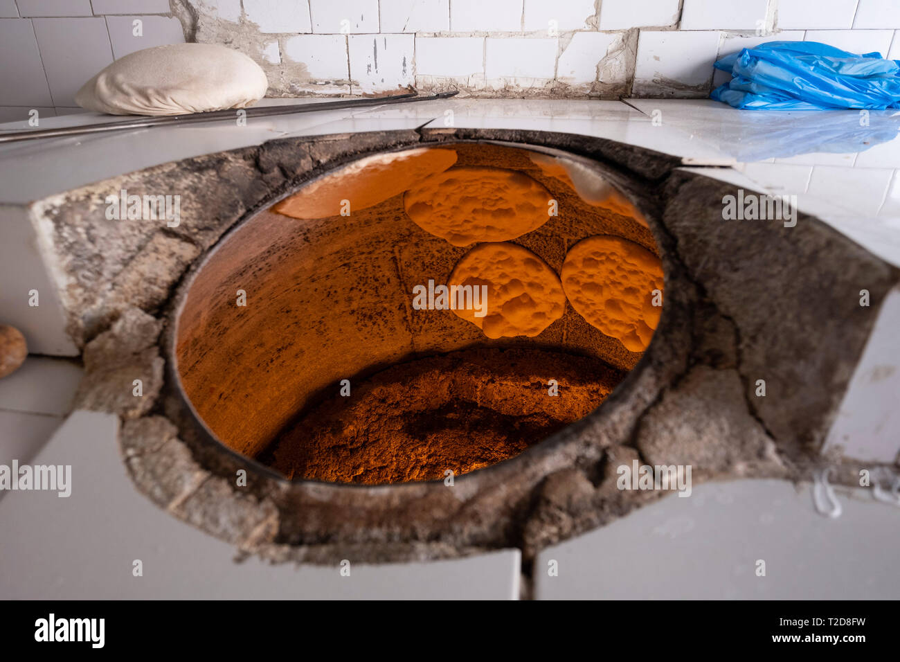 Bread being baked the arabic way on the walls of pita bread tandoor oven Stock Photo