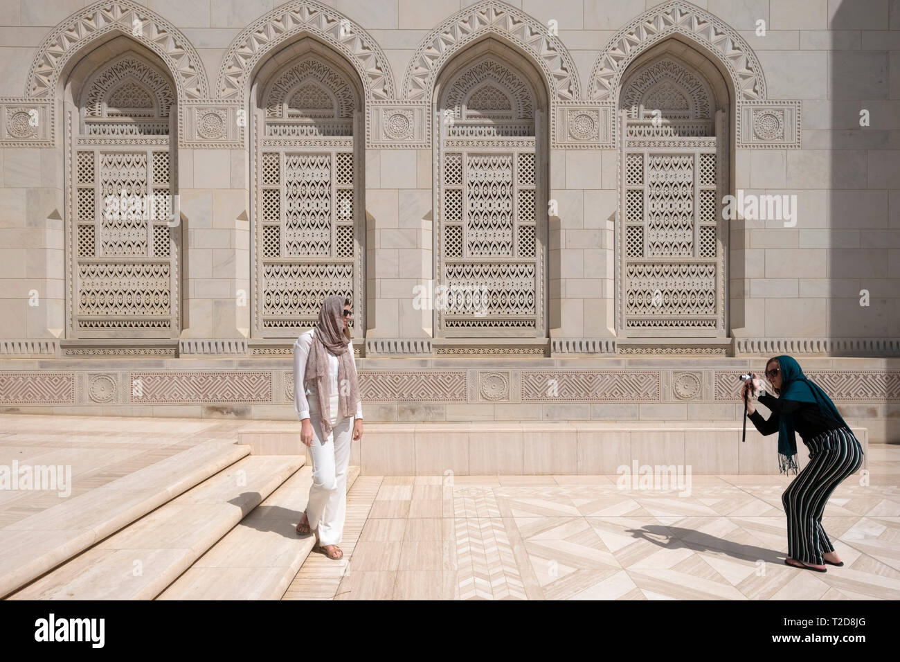 Tourist posing for photos at the Sultan Qaboos Grand Mosque, Muscat, Oman Stock Photo