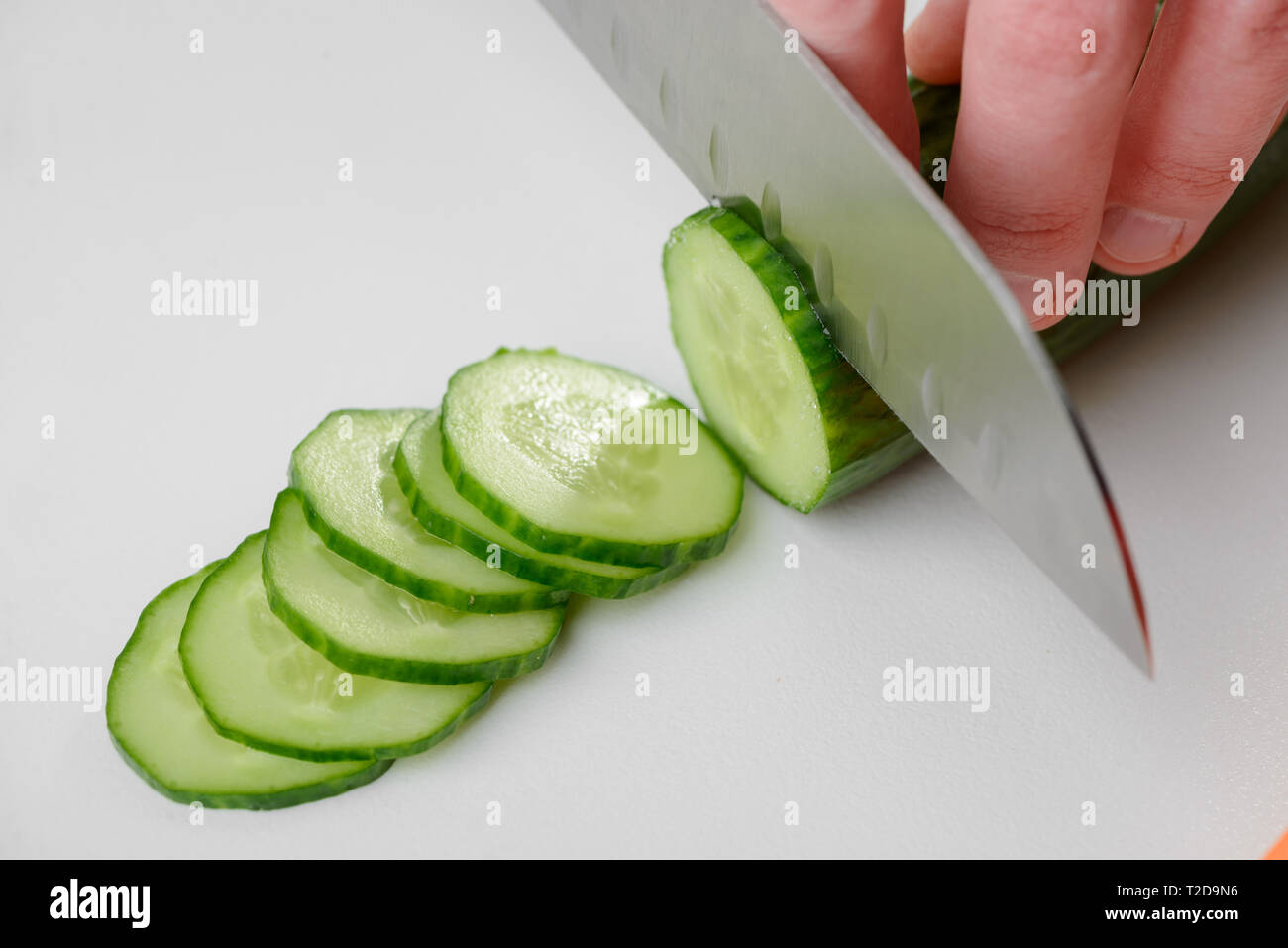 https://c8.alamy.com/comp/T2D9N6/man-cutting-a-cucumber-with-a-chefs-knife-thin-slices-of-the-vegetable-on-a-white-board-T2D9N6.jpg