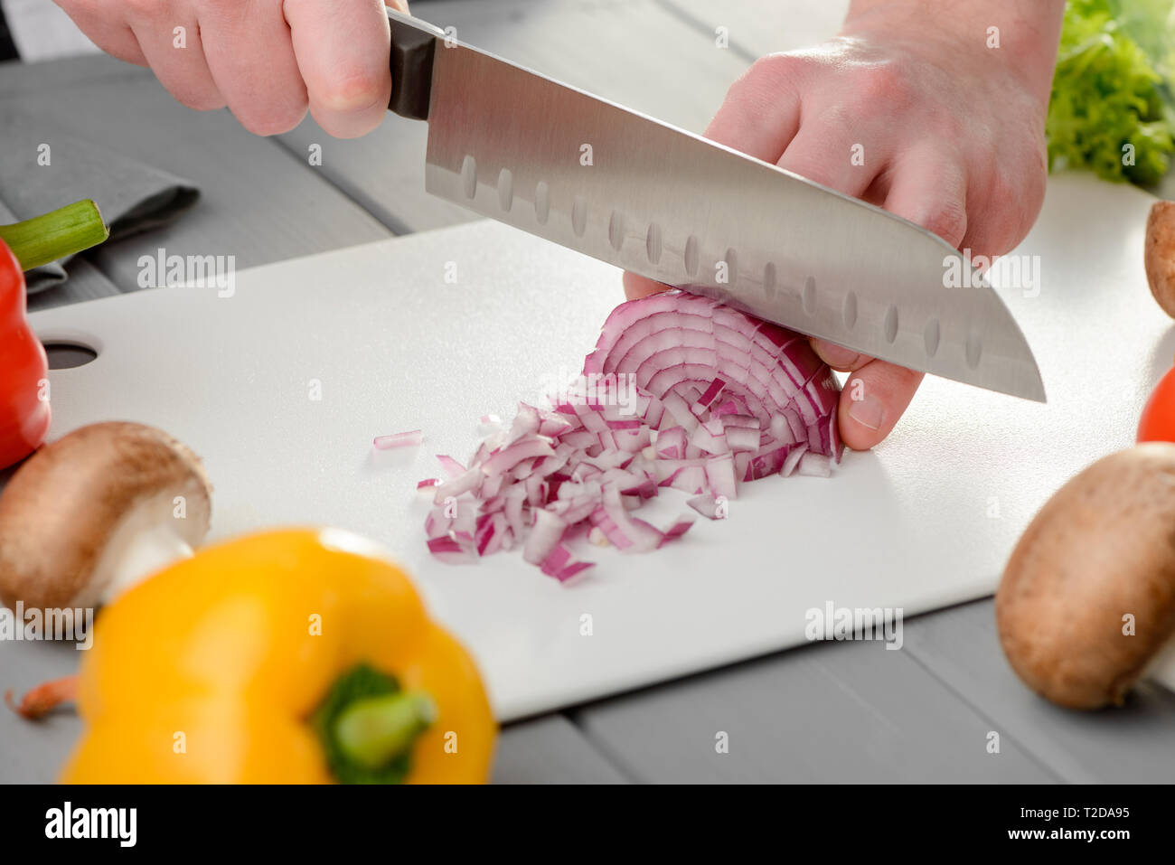 https://c8.alamy.com/comp/T2DA95/man-chopping-a-red-onion-into-medium-dice-using-a-chefs-knife-cutting-veggie-ingredients-on-a-white-board-kitchen-and-cooking-T2DA95.jpg