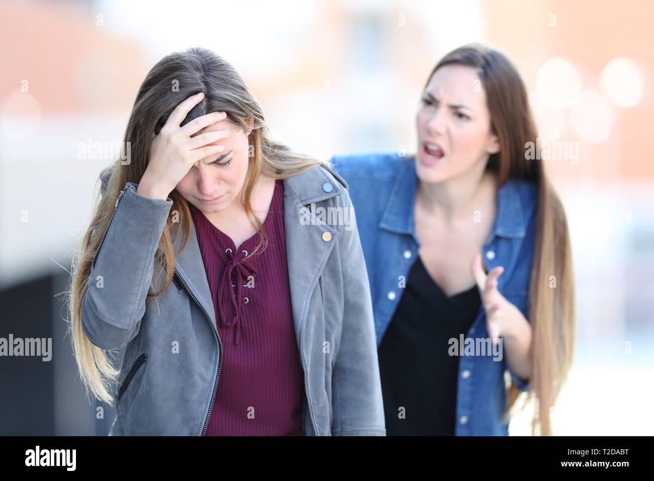 Mad girl scolding her concerned friend in the street Stock Photo