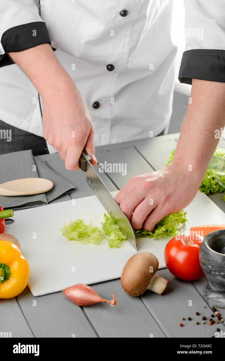 https://c8.alamy.com/comp/T2DARC/chef-chopping-lettuce-leaves-and-cutting-vegetables-for-a-salad-cooking-process-in-a-restaurant-T2DARC.jpg