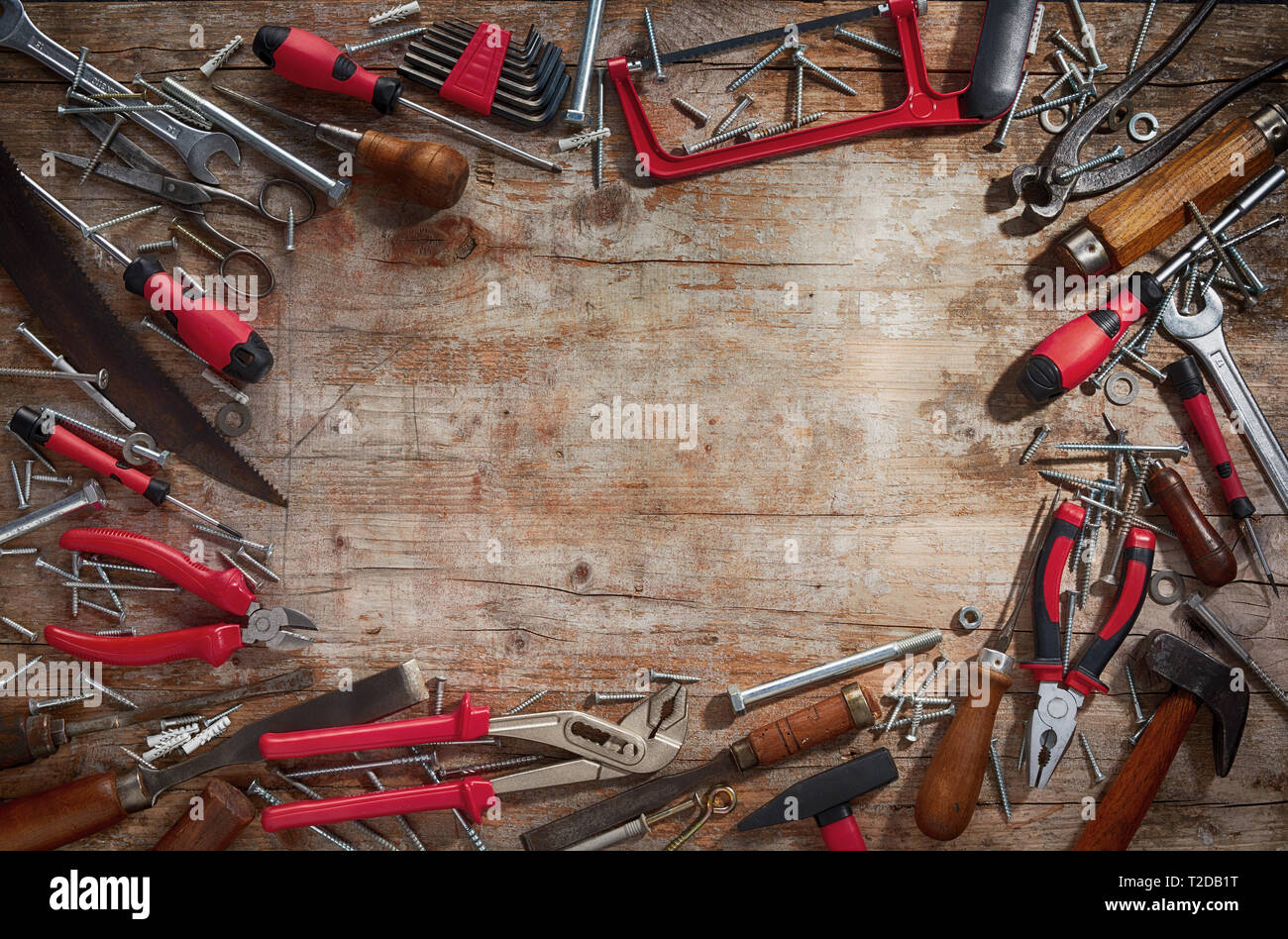 Frame of old vintage wood handled and modern red household hand tools on a weathered rustic wood background with central copy space from above Stock Photo