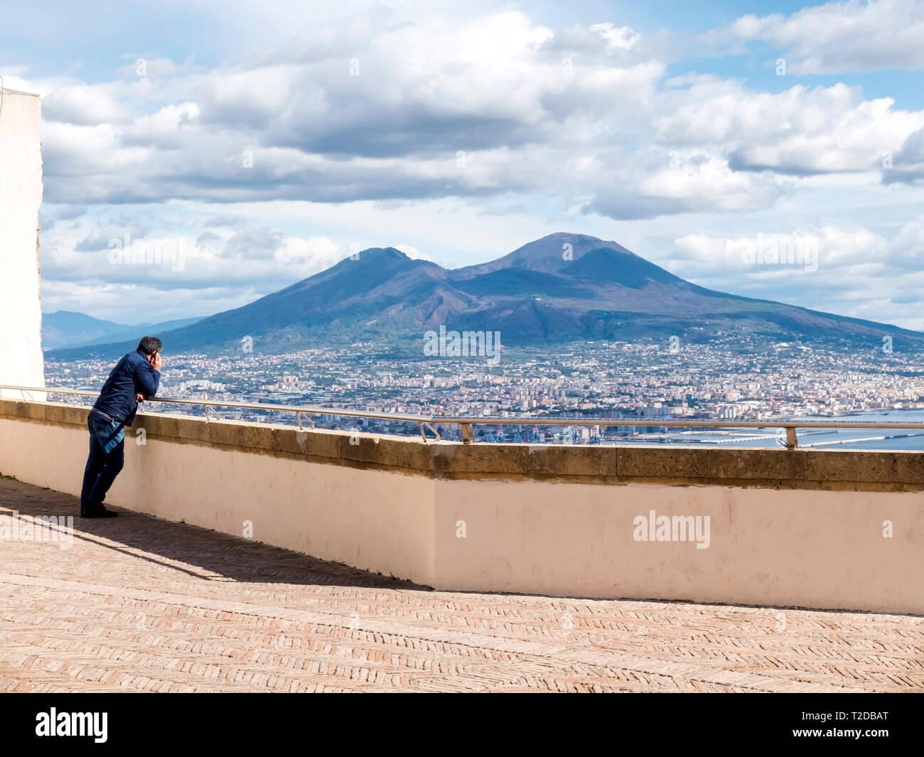 Man using mobile while leaning in a wall looking at Vesubio volcano Stock Photo