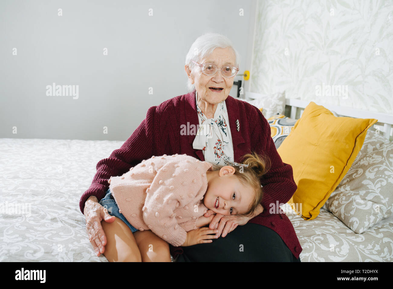 Happy moments with great grandma, senior lady spending quality time with her great granddaughter. Restless naughty little girl taking a nap on her gre Stock Photo