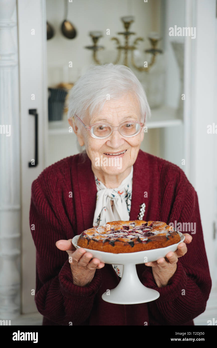 Senior gray haired woman presenting beautiful and tasty holiday pie ...