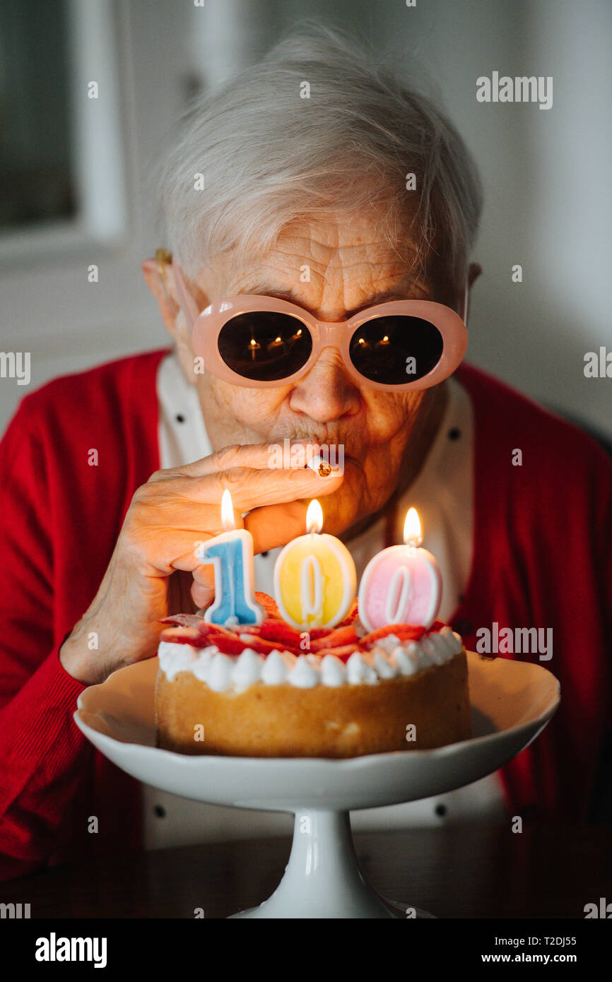 Senior happy well dressed gray haired woman is celebrating her 100th birthday at home. Stock Photo