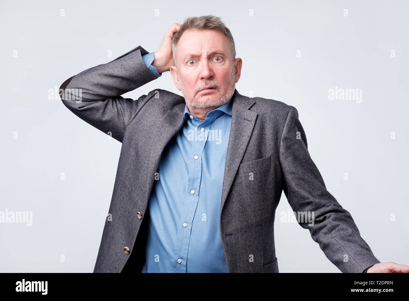 Pensive senior man in suit scratching his head. Being confused and upset by his finance. Stock Photo