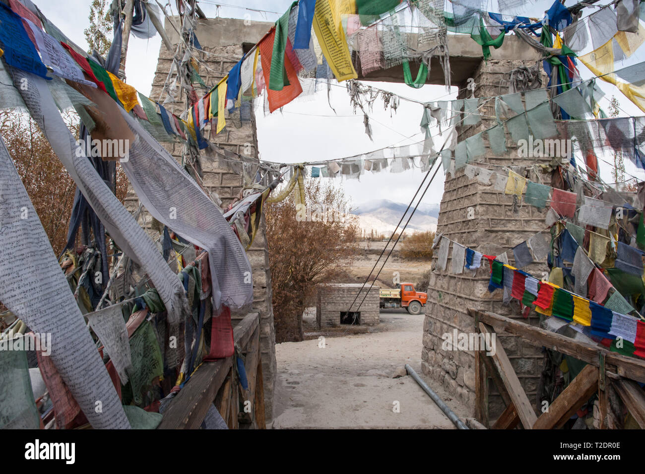 A stone arch way leading onto a bridge in Leh, Ladakh, covered in Tibetan prayer flags Stock Photo