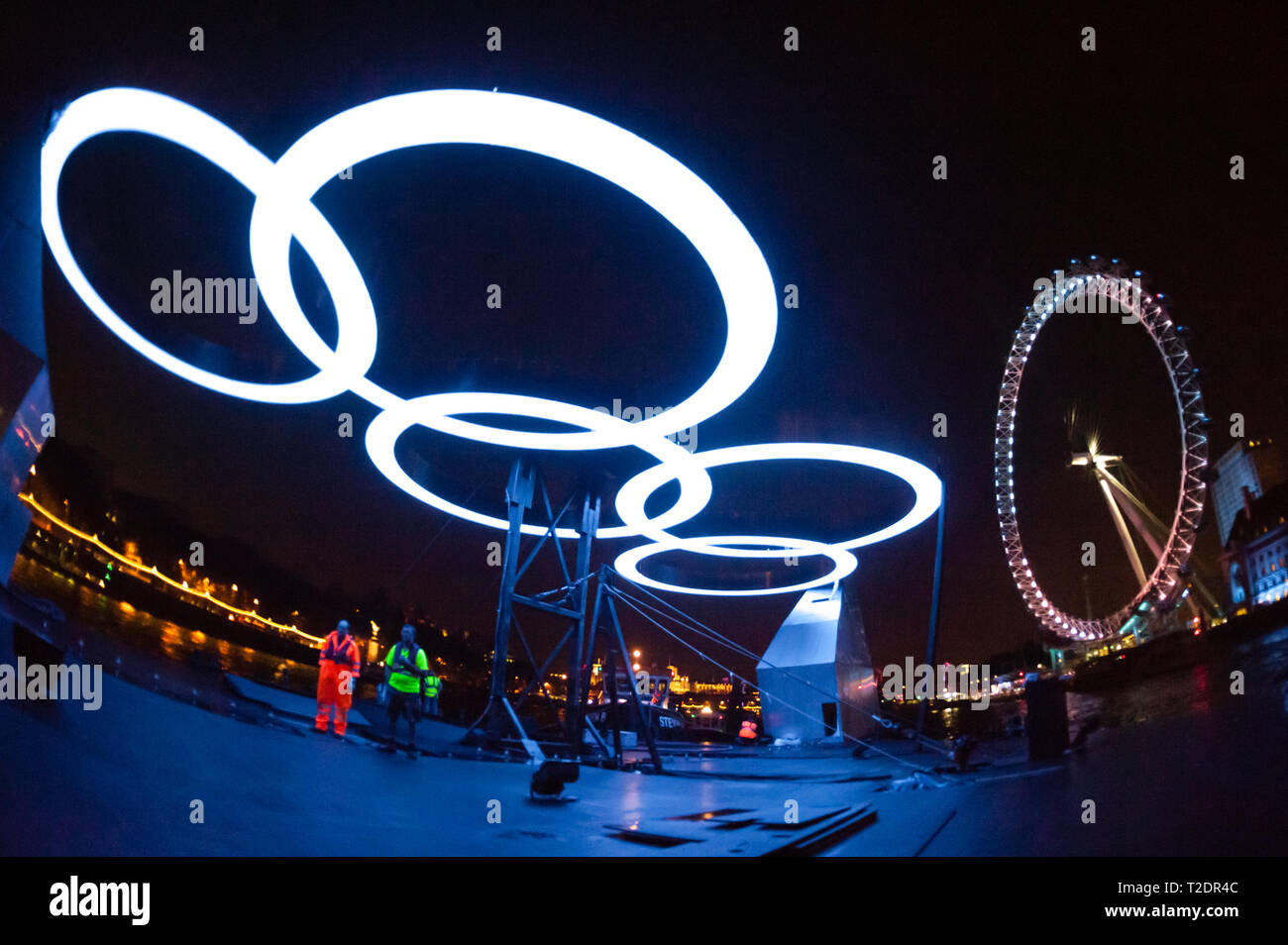 The Olympic Rings illuminate workers moving the, 'Rings on the River' exhibit, from Greenwich to the South Bank, during the London Olympic Games 2012. Stock Photo