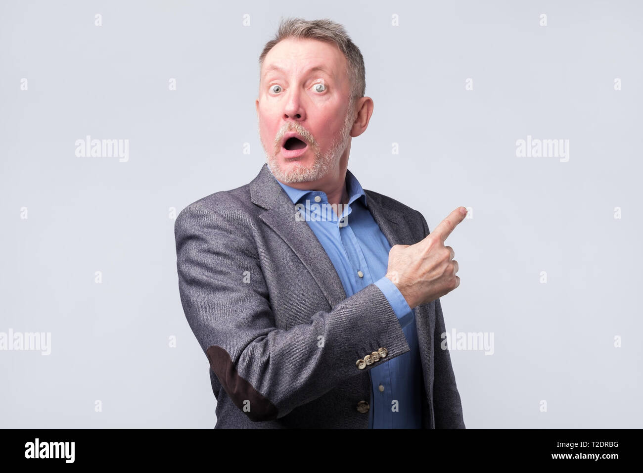 Surprised handsome senior man in suit with pointing with finger. Copyspace Stock Photo