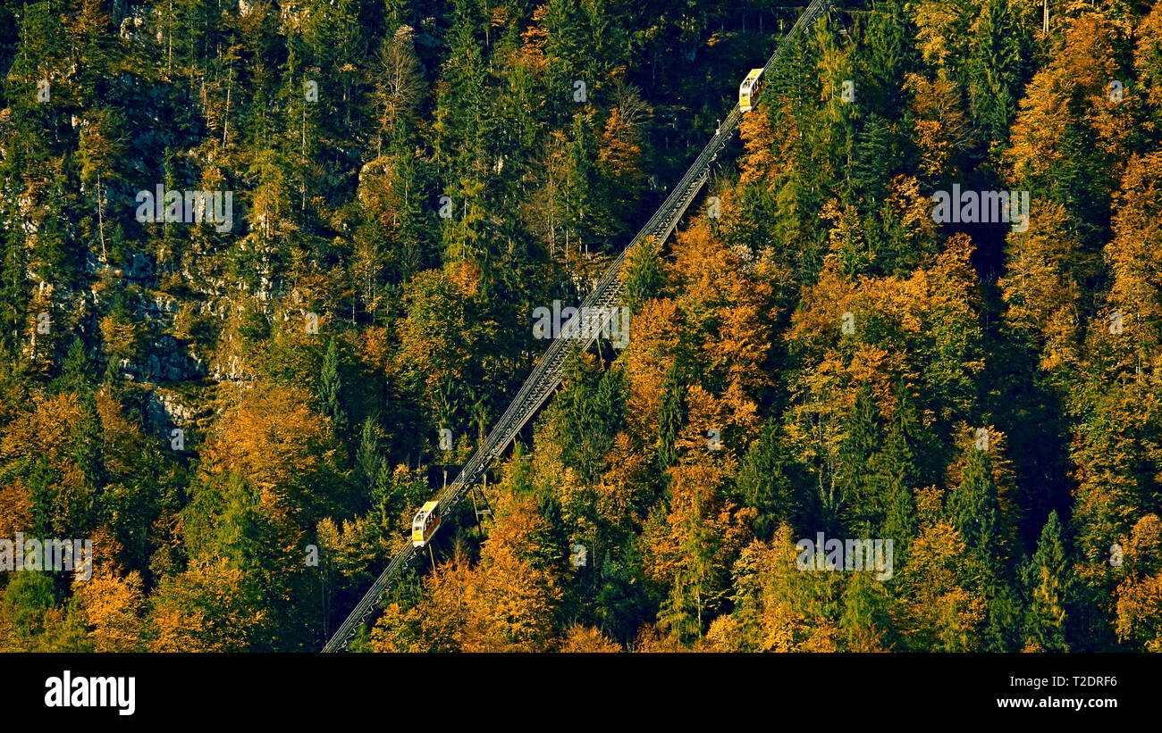 Beautiful aerial fall view of cable car ropeway funicular in austrian alps. Red cable railway car in the mountains by resort village Hallstatt, Salzka Stock Photo
