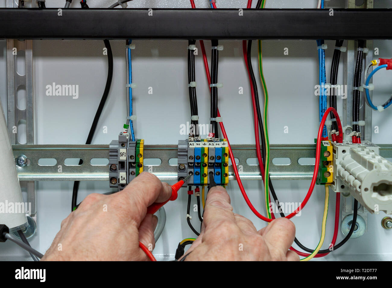 Electrical controls engineer testing circuit wiring in a control panel