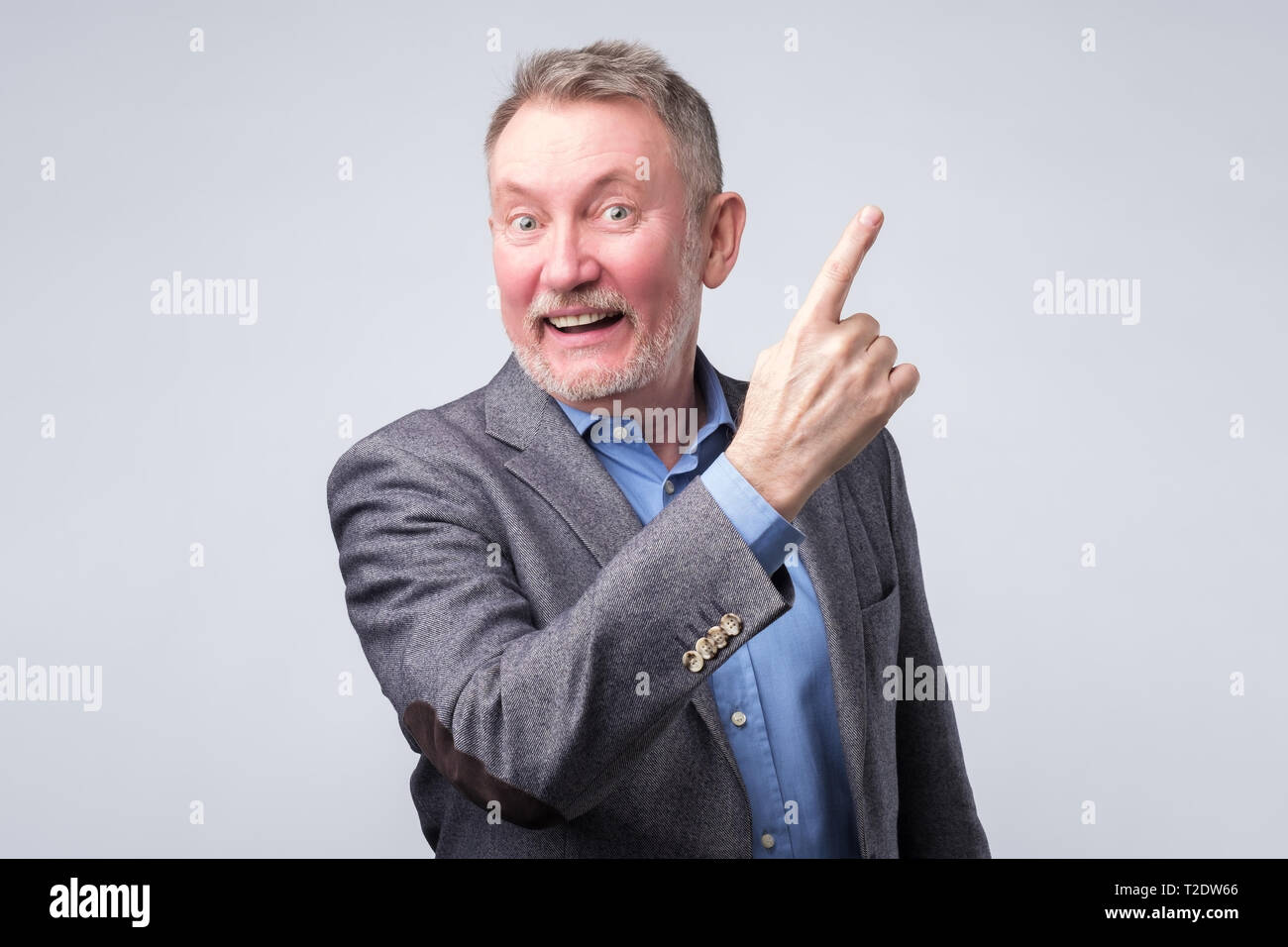 Happy handsome senior man in suit with pointing with finger. Copyspace Stock Photo