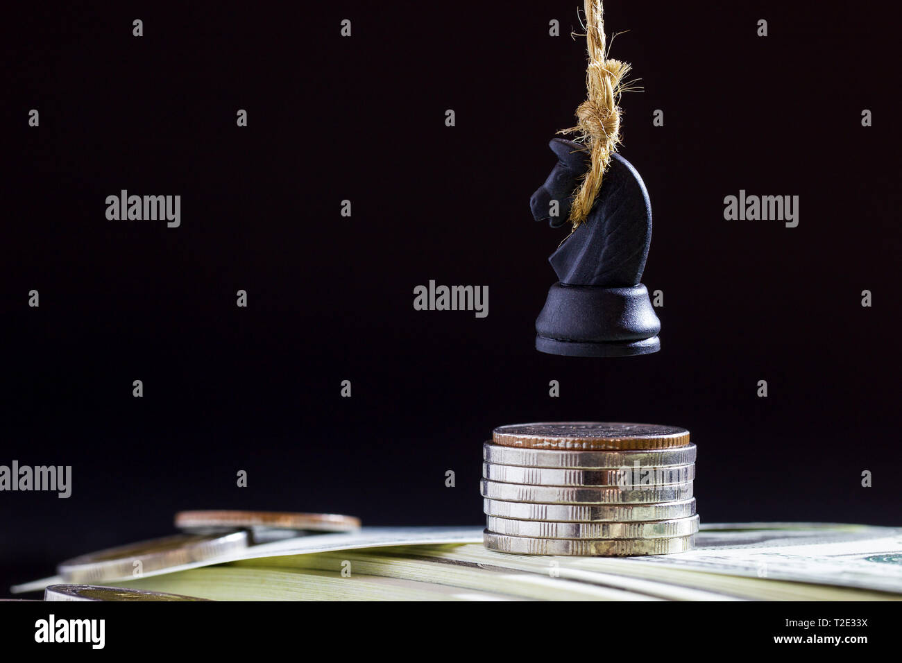 Horse or king of chess execute by hanging on dollar banknote and coin in darkness background. Concept of loss or business bankruptcy. Stock Photo