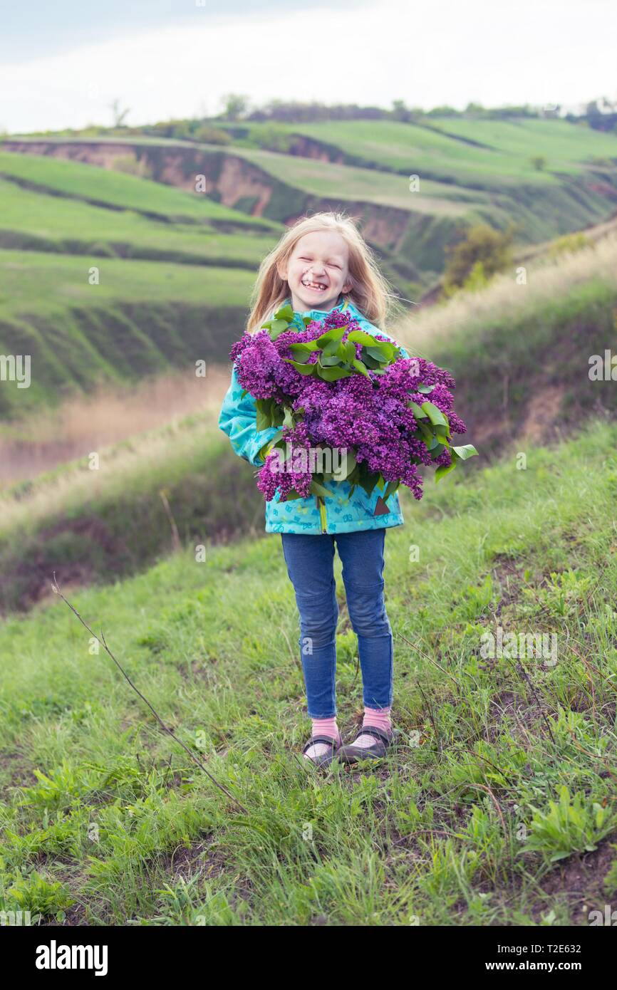 little happy girl with a bouquet of lilacs Stock Photo - Alamy