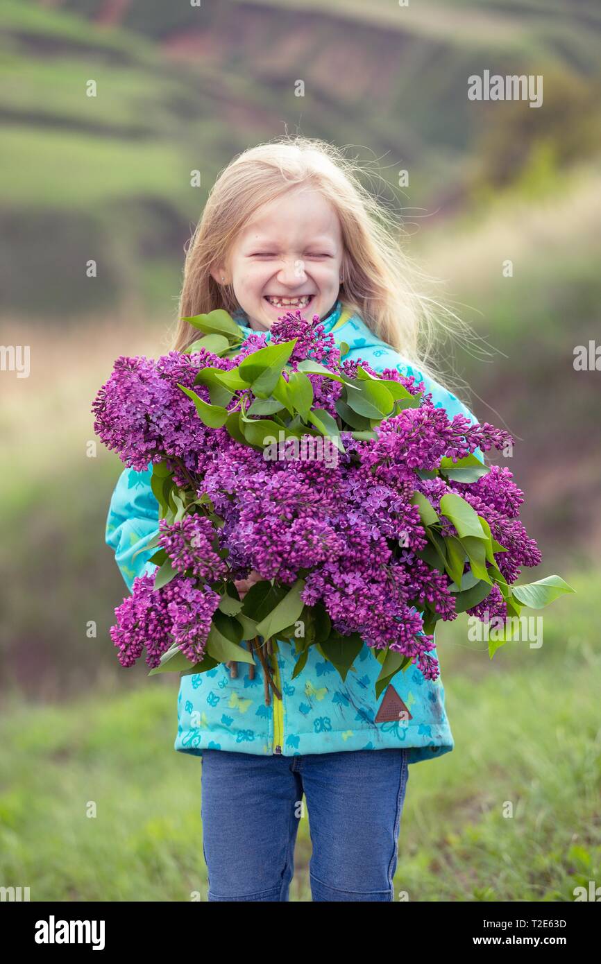 little happy girl with a bouquet of lilacs Stock Photo - Alamy