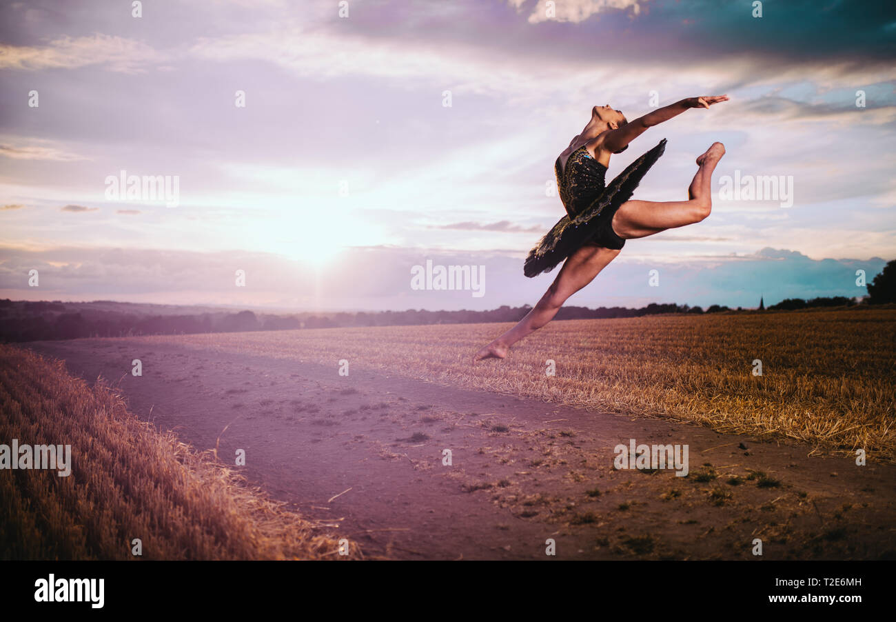 Ballet dancer leaping through air with sun setting in background. Stock Photo