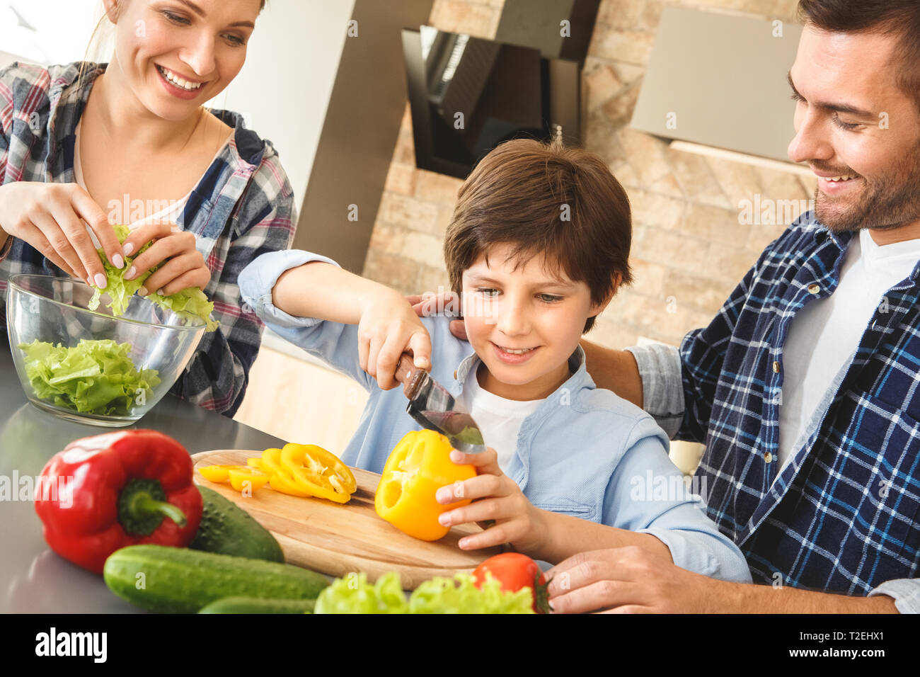 Mother father and son at home standing in kitchen together parents ...