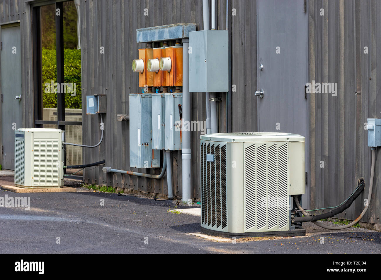 Horizontal shot of commercial air conditioners and electrical boxes outside an old office complex. Stock Photo