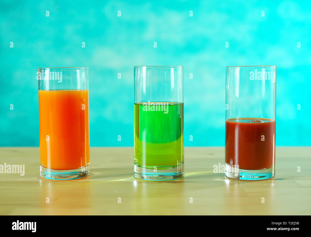 Fresh orange, apple and tomato juices in glasses in bright table setting. Stock Photo