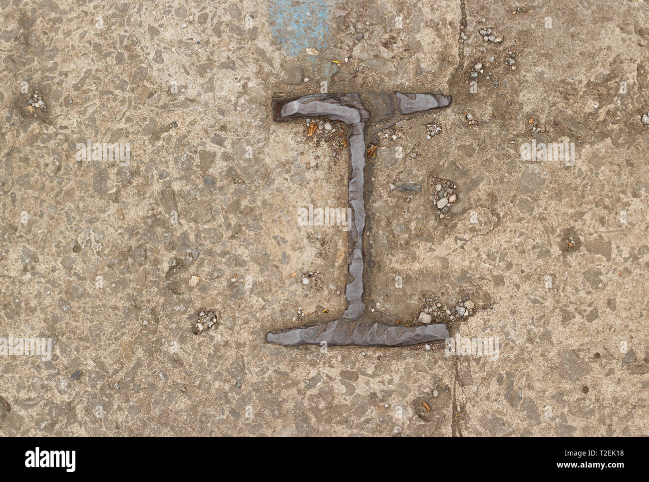 Detail of Cast Iron Number One or Letter I On Rough Concrete Ground Stock Photo