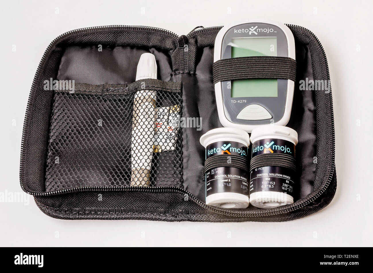 A Keto-Mojo ketone and blood glucose monitoring kit is pictured on white, with the meter, ketone and glucose test strips, and lancet device. Stock Photo