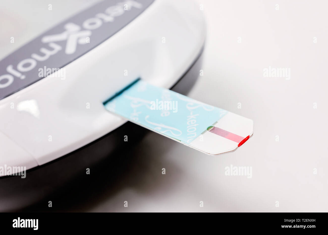 A Keto-Mojo ketone and blood glucose meter is pictured on white, along with a ketone test strip, March 30, 2019, in Coden, Alabama. Stock Photo
