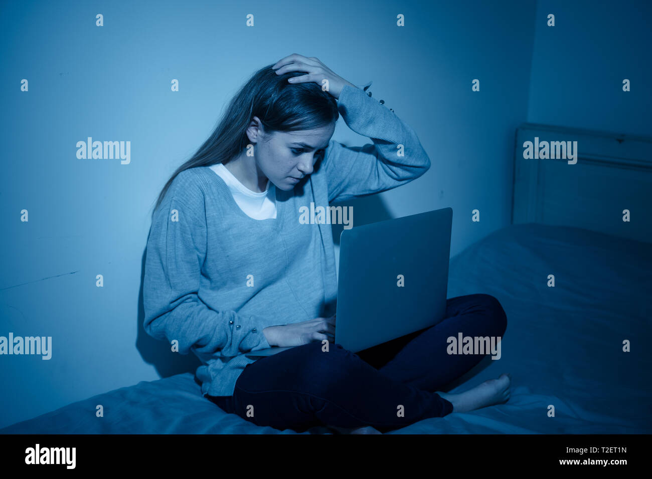 Scared and intimidated sad teenager bullied on line with laptop suffering cyberbullying and harassment. Child victim of bullying stalker social media, Stock Photo