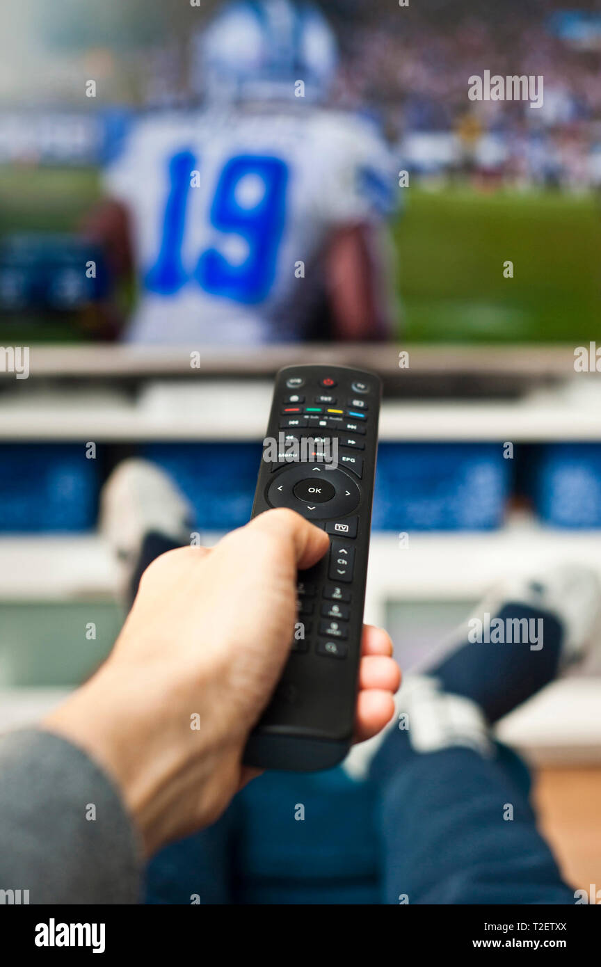 man hand holding a remote control pointed to a television screen Stock Photo