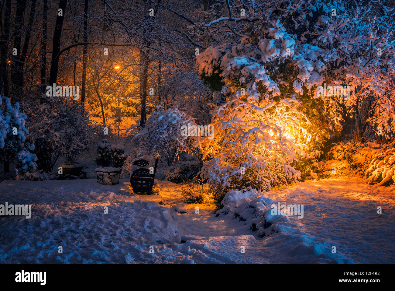 Beautiful winter scene with lots of snow and a bench on a silent night in a park after heavy snow falling in Bucharest Romania Stock Photo