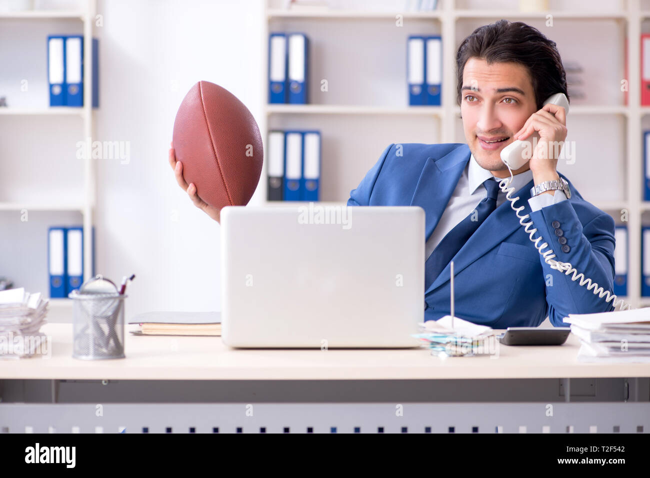 Young handsome businessman with rugby ball in the office Stock Photo ...