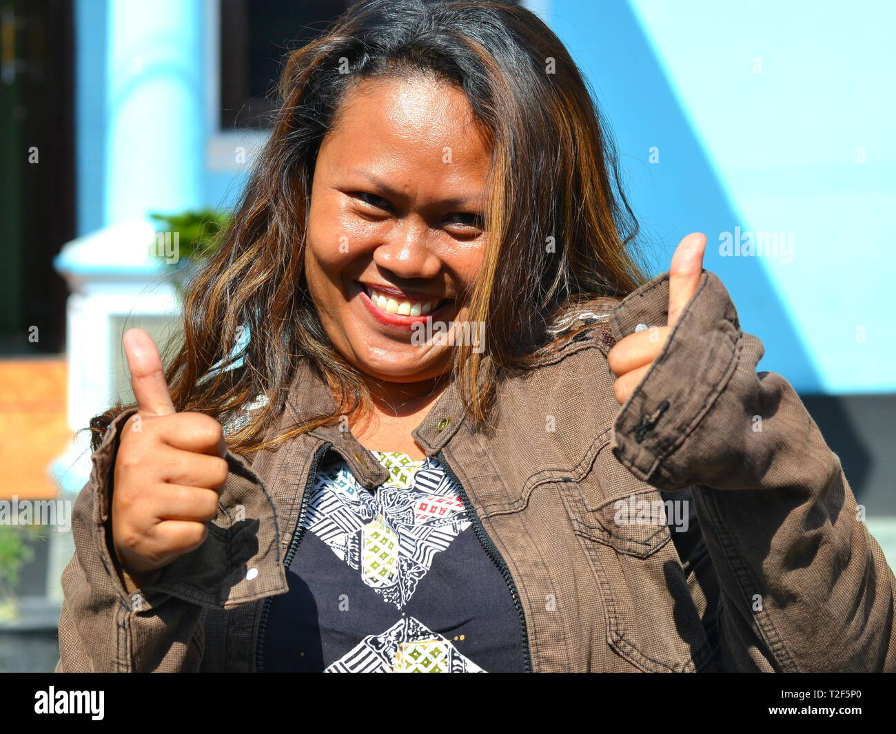 High-spirited young Indonesian woman gives two thumbs up. Stock Photo